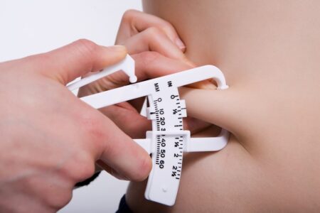 Person measuring their stomach measuring tape