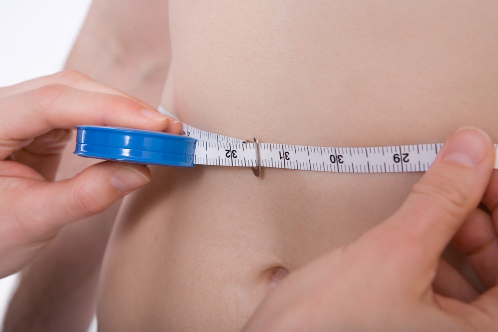 Woman measuring her stomach tape