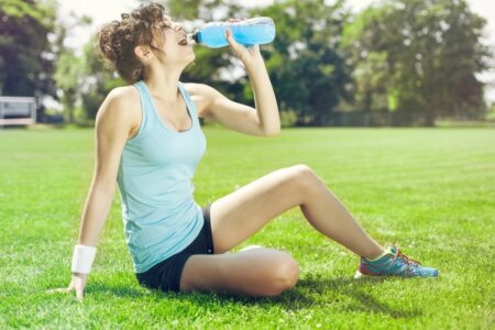 Woman sitting grass drinking water